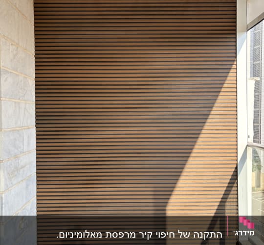 קיר עץ עם פסים אופקיים במרפסת מוארת בשמש
